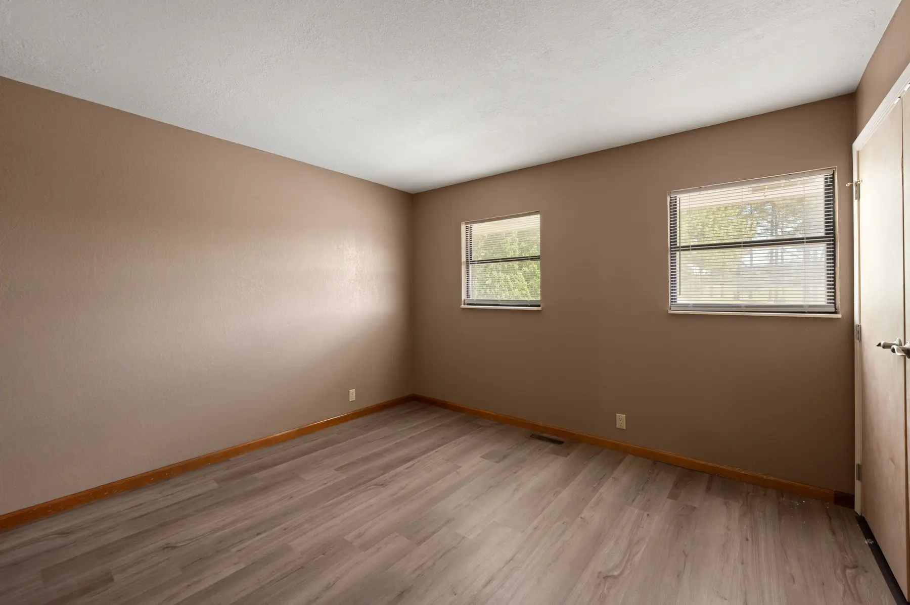 Second bedroom with updated flooring and two windows in Unit 101
