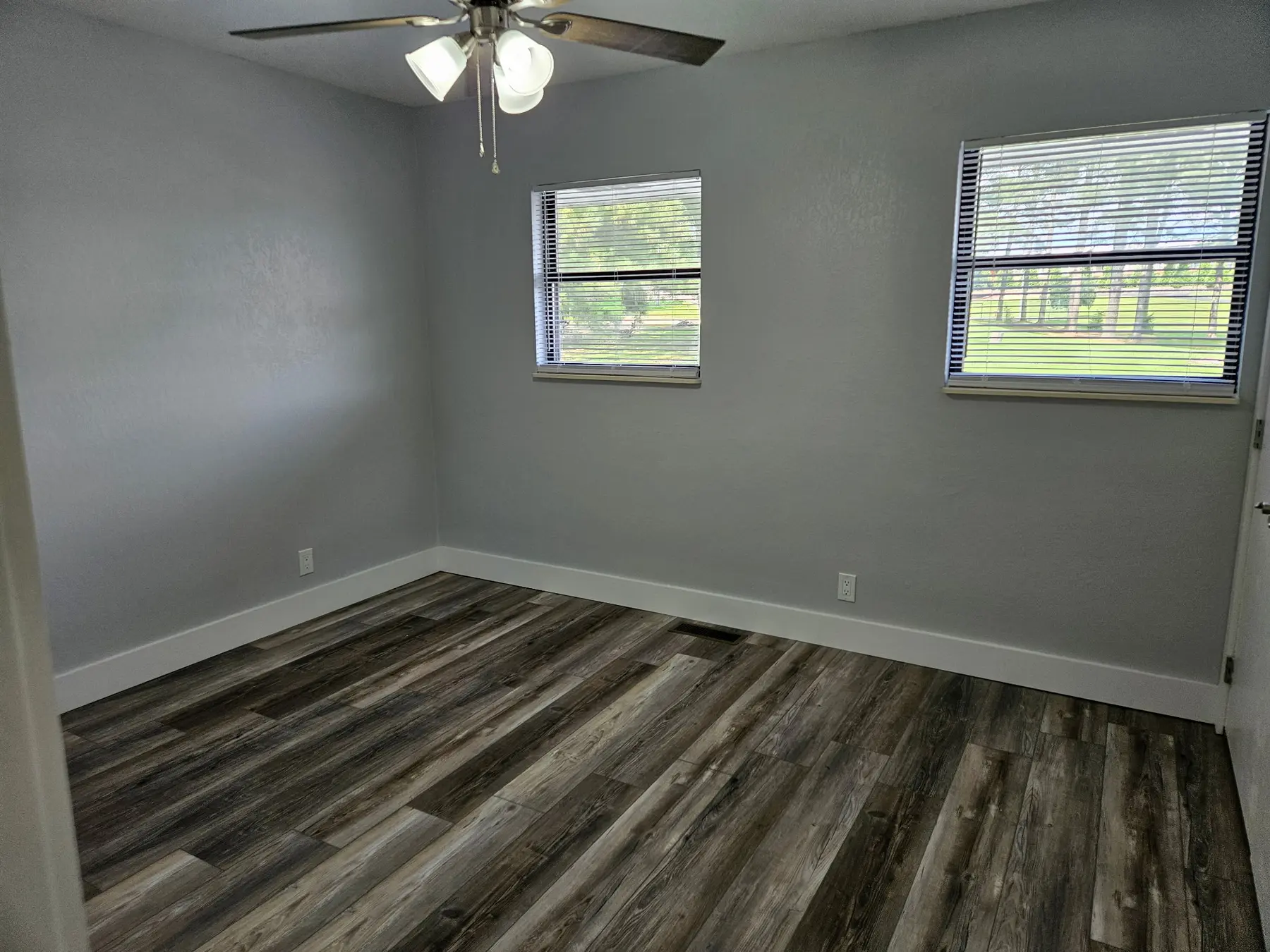 Second bedroom with new flooring and two windows in Unit 103
