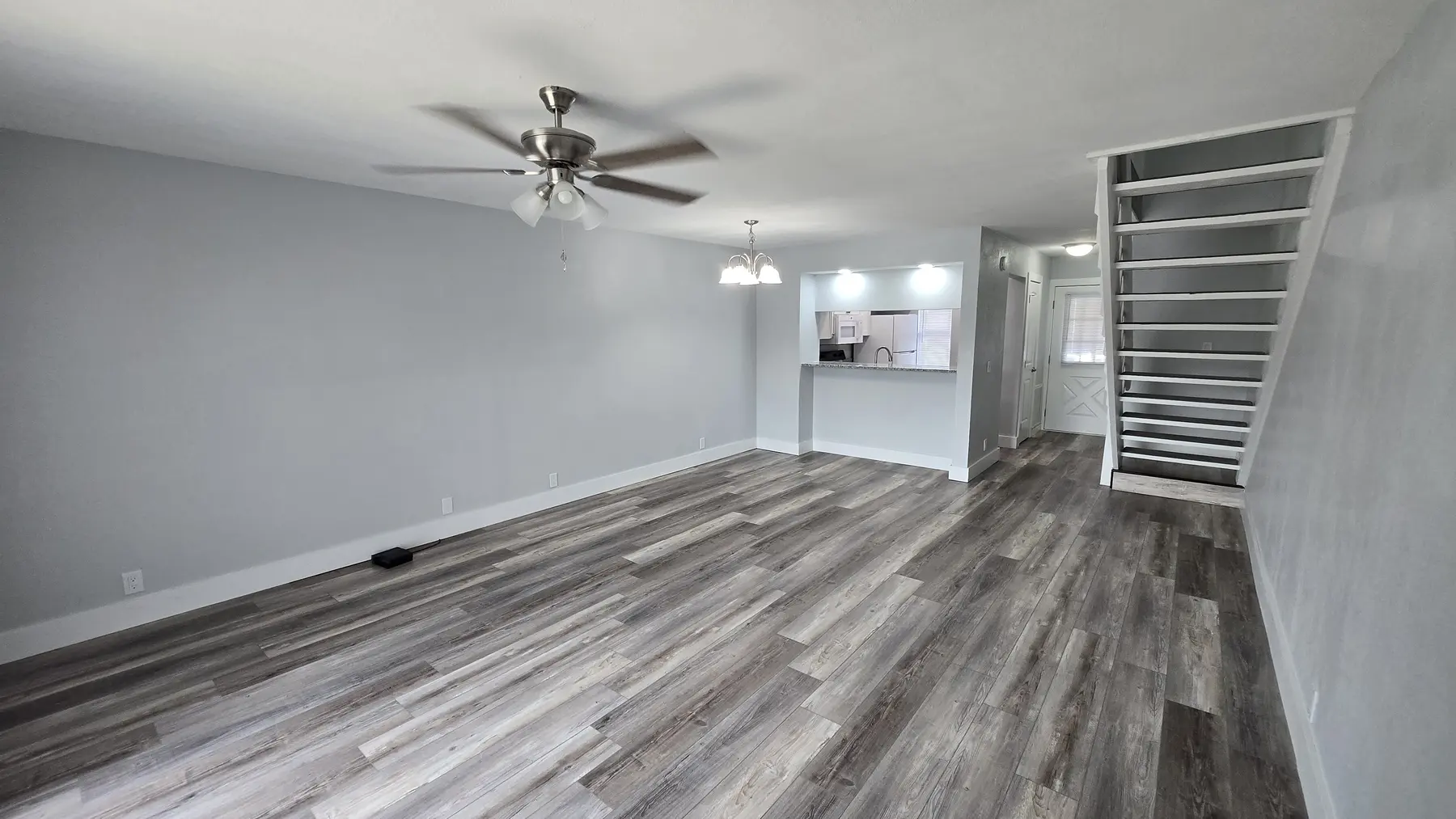 Updated living room with new flooring and staircase in Unit 103